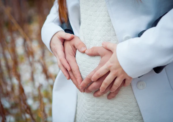 Pregnant Woman holding her hands in a heart shape on her baby bump. Pregnant Belly with fingers Heart symbol. Maternity concept. Baby Shower — Stock Photo, Image