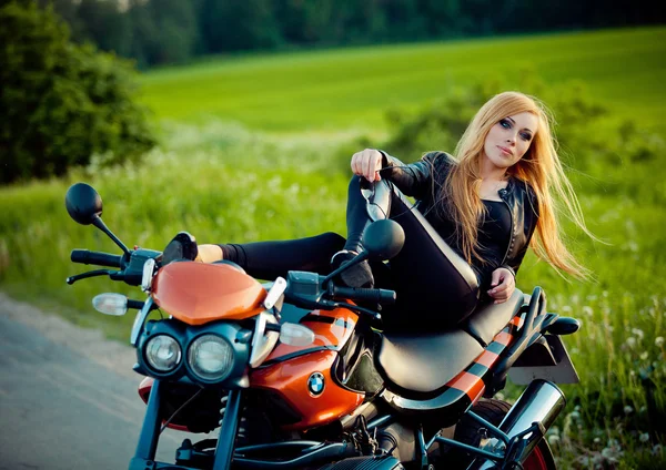 Kırmızı motosiklet üzerinde oturan genç seksi kadın — Stok fotoğraf