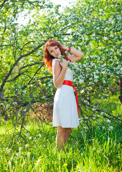 Free Happy Woman with Gorgeous Red Hair Enjoying Nature. Beauty Young Girl Outdoor in Spring Garden. Freedom concept. Healthy Smiling Girl over Green Flowers Nature Background. Apple-trees in Blossom — Stock Photo, Image