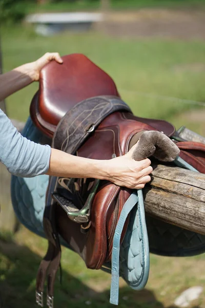 乗馬のための馬の鞍を取る手 — ストック写真