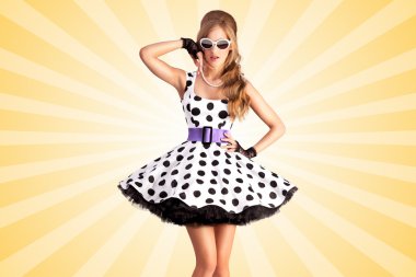 Noktalı elbise. Bir vogue pin-up kız Yaratıcı fotoğraf, bir retro polka-nokta elbise ve güneş gözlüğü giymiş, renkli soyut karikatür tarzı arka plan üzerinde poz.
