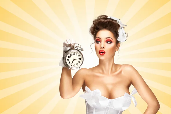 Always late. Sexy pinup bride in a vintage wedding corset holding a retro alarm clock and grimacing on colorful abstract cartoon style background. — Stock Photo, Image