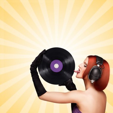 Tadına bak ve dinle. Baştan çıkarıcı bir kızın renkli fotoğrafı, büyük vintage müzik kulaklıkları takmak ve renkli soyut çizgi film tarzı arka planda mor lp microgroove vinil kayıt yalama.