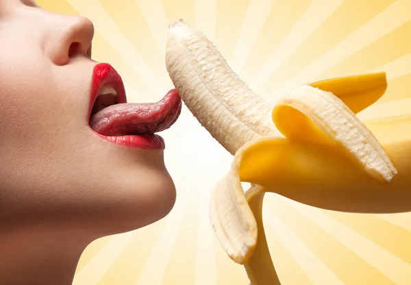 健康生活的美味方式。一个热的女孩的脸，舔一个半皮的黄色香蕉在五颜六色的抽象卡通风格背景. — 图库照片