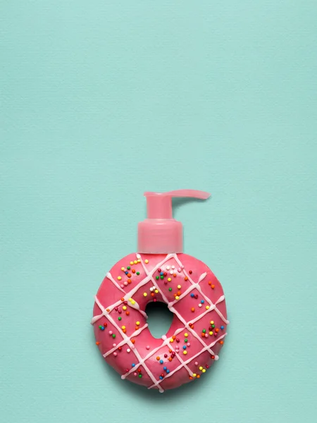 Donut pomp. Creatieve stilleven van een smakelijke zoete donut met een cosmetische pomp-dispenser op blauwe achtergrond. — Stockfoto