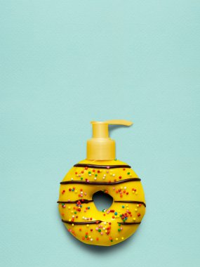 Çörek pompa. Mavi arka plan üzerinde bir kozmetik pompa dispenseri ile lezzetli bir tatlı sarı donut yaratıcı natürmort.