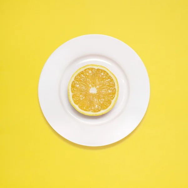 Zitrone zum Frühstück. Zitronenscheibe auf weißem Teller auf gelbem Hintergrund. — Stockfoto
