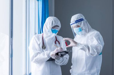 Beyaz arka planda iki doktor kan örneği tüpü tutuyor. Coronavirus ya da COVID-19 salgını kavramı, Coronavirüs 'ün yayılmasını önlemenin yollarını bulma kavramı,.