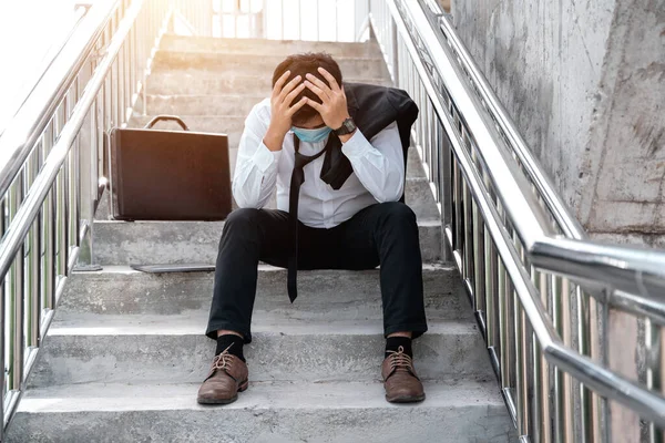 Unemployed stressed young Asian business man in suit covering face with hands. Failure and layoff concept to the disease Covid-19,Work and stress. business people despair low economic crisis