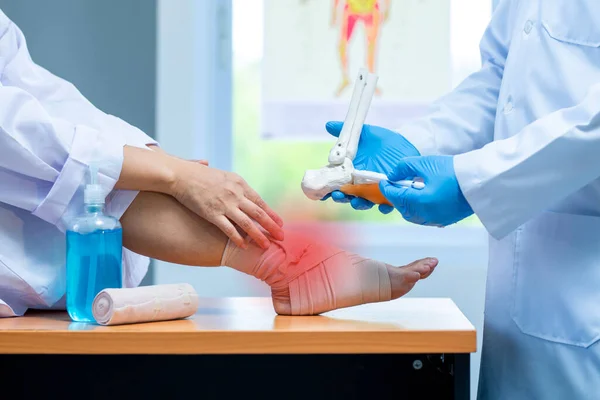 close up hand wear medical gloves doctor in medical gloves holds artificial boneof the foot and examines a sore ankle in clinic, Concept of medical orthopedic treatment