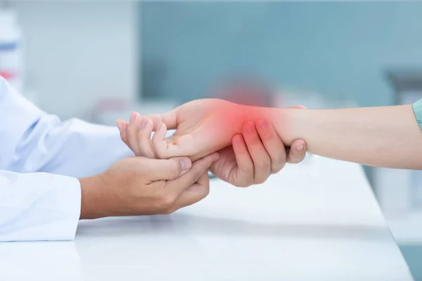 Doktor, diz üstü bilgisayardaki uzun çalışmanın yol açtığı bilek ağrısı olan kemik sorunlu hastayı muayene ediyor. Karpal tünel sendromu, artrit, nörolojik hastalık konsepti. Elin uyuşması.