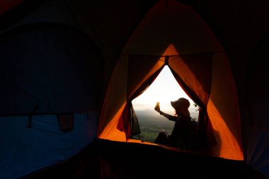 Dağlarda selfie çeken bir kadının silüeti. Kamp gezisi, yaşam tarzı