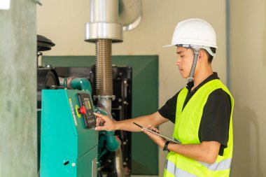 Asyalı bakım teknisyeni fabrikadaki su basıncı kontrol sistemi ekipmanlarının teknik verilerini kontrol ediyor..