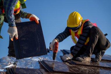 İşçi kapatma yeni seramik kiremit çatı döşeme çatısı çatısı çatısı çatı inşaat alanında kullanılan elektrikli matkap ile.