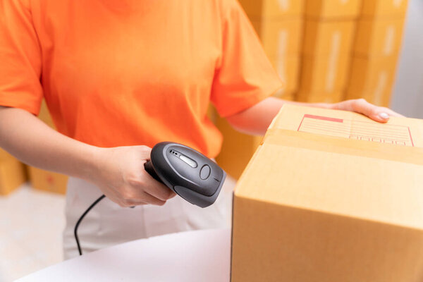 Close up hand of parcel delivery worker in warehouse with barcode scanner.