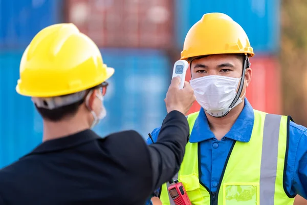 亚洲工人使用数字温度计扫描体温 向工业建筑工地工作人员提供卫生面罩 以保护他们免受考罗纳维勒斯或Covid 19的感染 新常态 — 图库照片