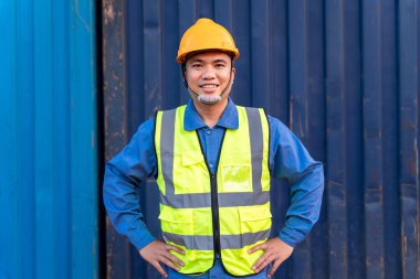 Asyalı işçilerin portresi ithalat ve ihracat malları konteynır arka planında bir kask mantığı taşıyorlar.