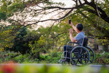 Engelli adam rahatla ve internetten parkta tekerlekli sandalyede telefon et..