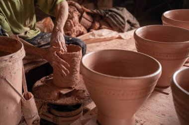 Çömlekçi çarkında çalışan adamların eli yakın. Eller kilden bir havan topu yontuyor. Tayland 'daki çömlekçinin tekerinde el yapımı kil eşyalar..