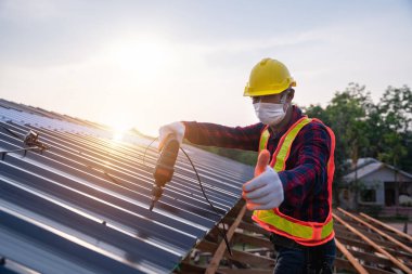 Yeni çatı metal levhası, çatı inşaat konseptine elektrikli matkap aletleri kullanarak inşaat işçilerinin güvenliği için mutlu yıllar..