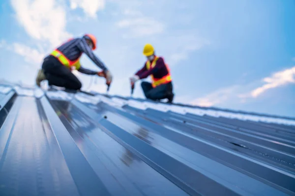 Seçici odak çatısı, yeni çatı metal levhası üzerine elektrikli matkap kullanan inşaat işçisi giyimi, çatı inşaat konsepti.