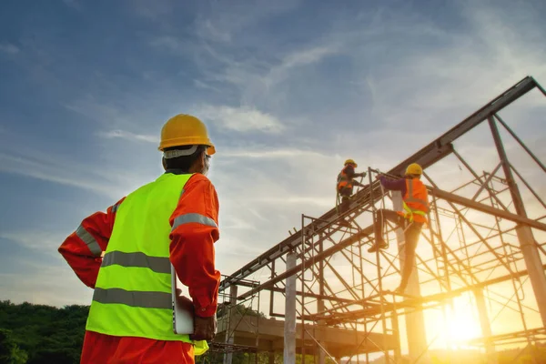 Engineer working on building site, Engineer technician watching warehouse steel roof structure , Engineer technician Looking Up and Analyzing an Unfinished Construction Project.