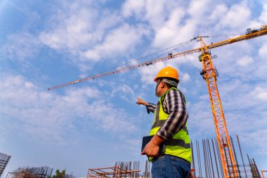 İnşaat mühendisleri teknisyenleri inşaat sahasındaki vakıf projesini kontrol eden vinç standında çalışıyor.