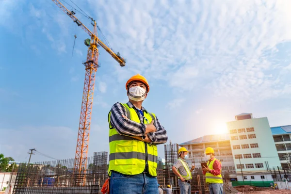 Team work of Construction engineers technician and  architect supervising progress stand in control of building foundations project and crane background at construction site