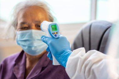 CORONAVIRUS COVID-19 konsepti, Asyalı üst düzey kadın Coronavirus için termometre silah taraması yapan bir maske takıyor ve Coronavirus veya COVID-19 hastalığının hastanede yayılmasını engelliyor.