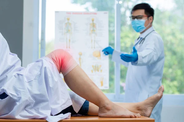 Selective focus knee, Orthopedic doctor wear medical gloves doctor examining head of patient with knee problems inflammation in clinic.