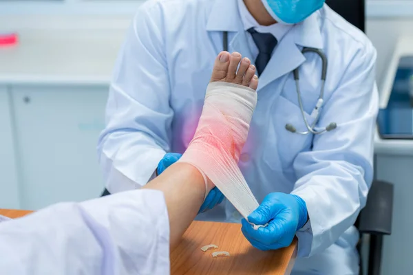 Close-up hand of orthopedic doctor wear medical gloves  Of Doctor Hand Tying Bandage On The Leg Of Patient In Clinic, osteophytes and heel, inflammation