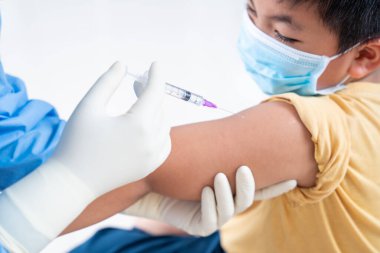 Doktor hasta çocuk ya da çocuğun omzunda aşı yapıyor. Koluna grip aşısı, koronavirüs, covid-19 aşısı aşısı, insan klinik denemelerine hazırlanıyor.