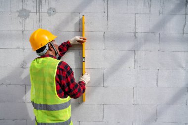Su seviyesini kullanarak tuğla ustası. Otoklavize beton blokların eğilimlerini kontrol et. İnşaat alanına duvar örme, tuğla yerleştirme