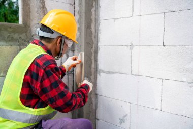 Tiler duvara büyük format döşemesi kuruyor. İnşaat alanında ev dekorasyonu