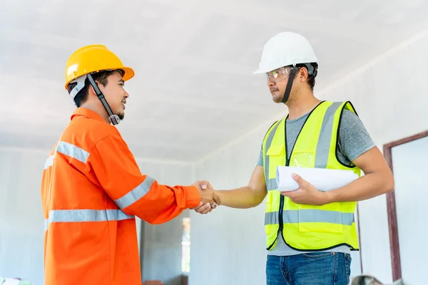 在建筑工地工作的剪贴板上给出指导后 亚洲建筑师和工程师与工头握手 — 图库照片