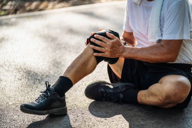 Parktaki antrenman sırasında diz ağrısı çeken yaşlı adamın yakın çekimi..