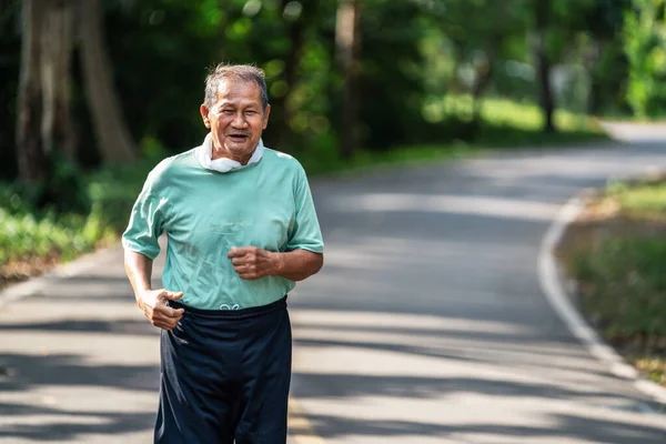 Asian senior mature man running jogging in park for good health.