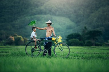 Taylandlı baba ve oğulun kırsal kesimde okul sonrası keyfi, evlat ve baba kırsal Asya 'daki aile çiftçilerinin yaşam tarzı. Tayland kırsalında geleneksel çiftçi hayatı. 
