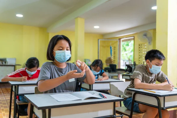 Ασιατικά Παιδιά Στην Τάξη Φορώντας Μάσκες Προσώπου Και Χρησιμοποιώντας Αντισηπτικό — Φωτογραφία Αρχείου