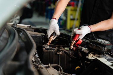 Akü denetimi, akü denetimi, akü kablolarından elektrik geçen bir arabanın aküsünü şarj eden el kapatılıyor.
