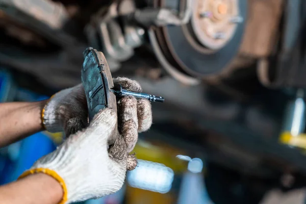 Car mechanic or serviceman checking a disc brake and asbestos brake pads it\'s a part of car use for stop the car for safety in auto repair service center