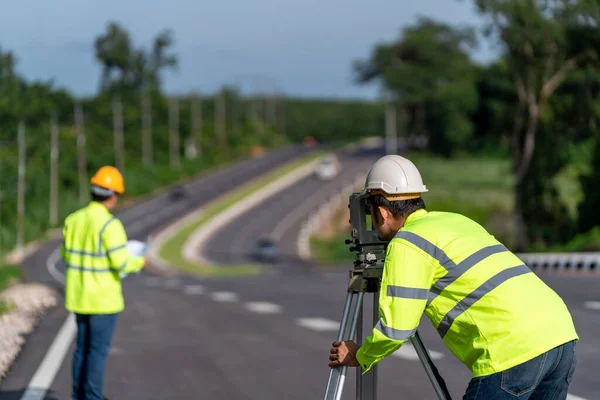建設道路工事中のセオドライト機器を用いて測定を行う測量技術者のチームワーク 土木技術者 測量機器 — ストック写真