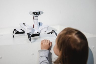 Küçük kız alışveriş merkezindeki bir sergide robot bir oyuncakla iletişim kuruyor. Gelecekteki çocuklar için küçük robot yardımcıları kavramı.