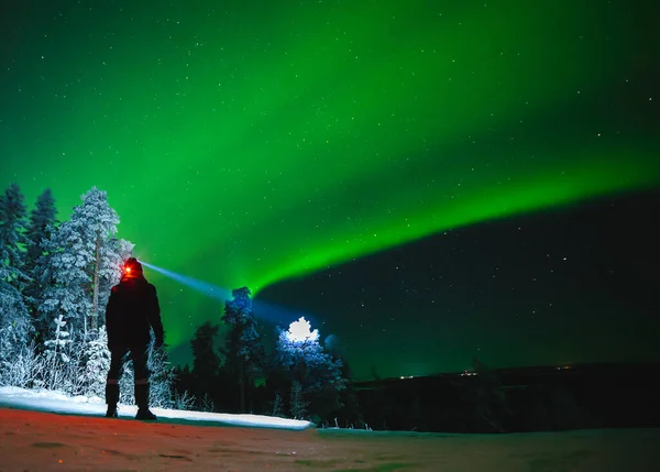 Un voyageur avec une lampe frontale profite de la vue sur les aurores boréales et l'espace. Photo iso haute — Photo