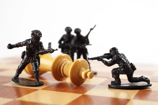 War concept. Toy soldiers kill chess King. Death of king. — Stock Photo, Image