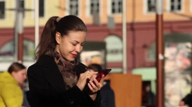 Genç kadın manifatura smartphone cep telefonu ile şehir içinde. Bir telefonda yazarak yakın çekim kız parmak.