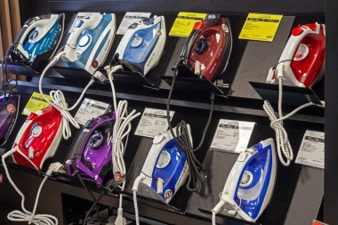 Yeni demirler. Ev aletleri dükkanında çeşitli demirler var. Mallarla rafa kaldırıyorum. Minsk, Belarus - Mart 2021