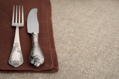 Tablo ayarı. Vintage çatal ve bıçak ile keten masa örtüsü ve boşaltmak kahverengi peçete üzerinde.