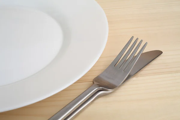 Placa vacía con tenedor y cuchillo en la mesa de madera — Foto de Stock