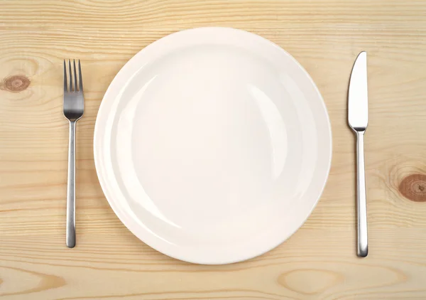 Empty plate with fork and knife on the wooden table — Stock Photo, Image